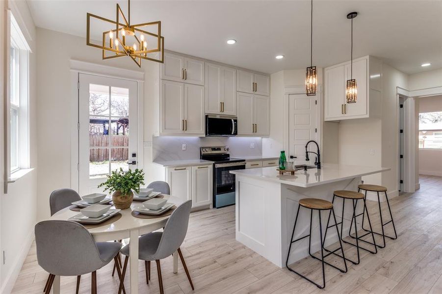 Kitchen with light wood finished floors, a healthy amount of sunlight, appliances with stainless steel finishes, and a chandelier