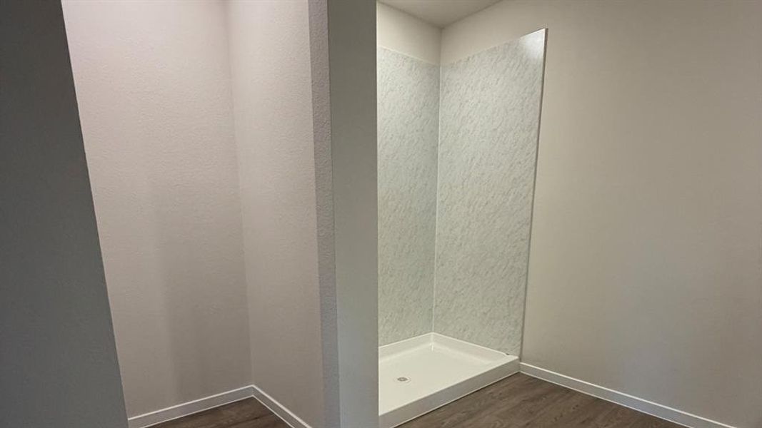 Full bath featuring a stall shower and dark wood-style floors