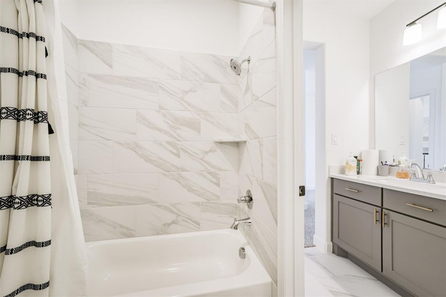 Upstairs bathroom featuring a tub and shower enclosed in sleek ceramic tile. Upstairs bathroom featuring a tub and shower enclosed in sleek ceramic tile.