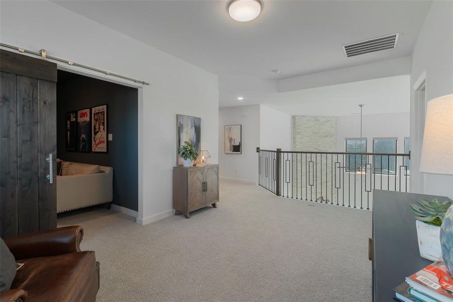 Hallway with carpet floors, a barn door, visible vents, and baseboards