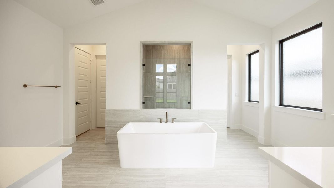 Full bath with healthy amount of natural light, lofted ceiling, a freestanding tub, a stall shower, and vanity Full bath with healthy amount of natural light, lofted ceiling, a freestanding tub, a stall shower, and vanity