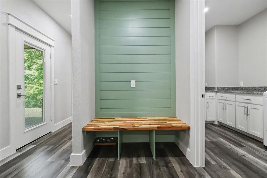 Built-in bench with a natural wood-finish top and green shiplap accent wall