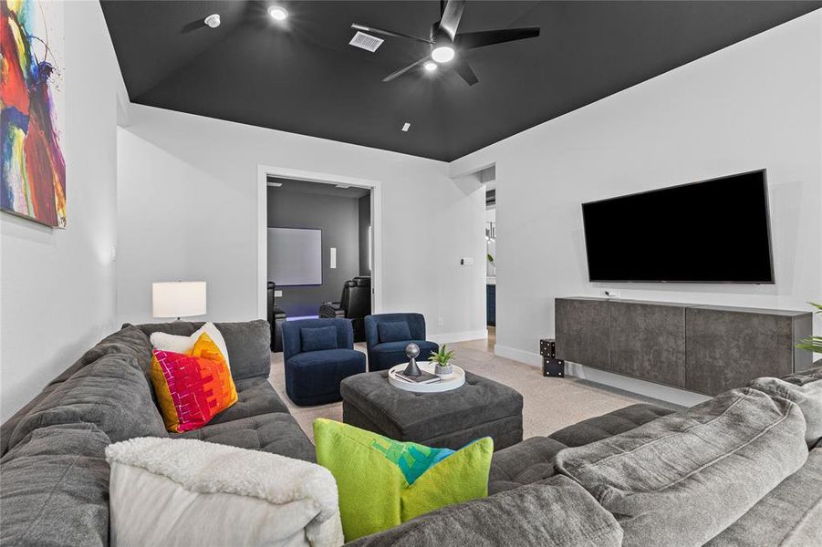 Living area featuring carpet flooring, ceiling fan, and vaulted ceiling