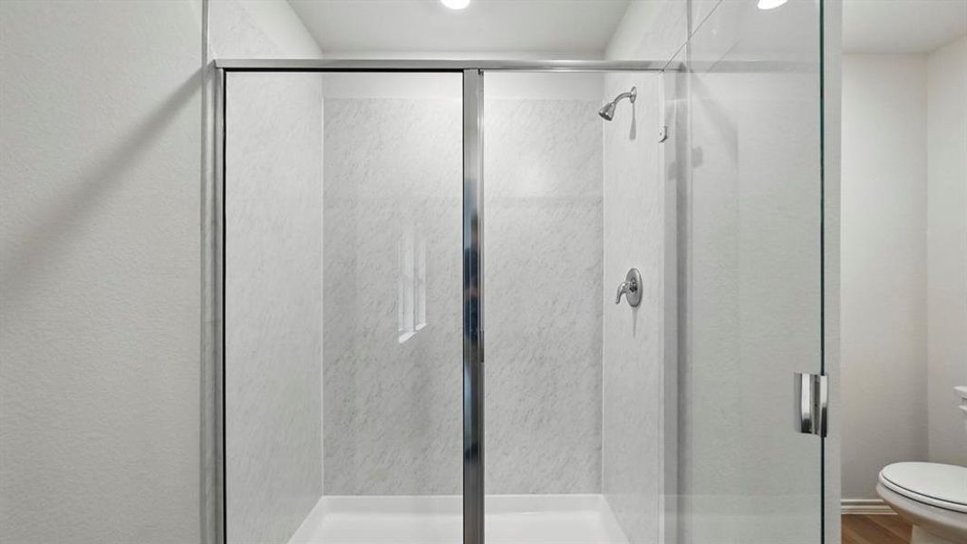 The bathroom includes a shower with a sliding glass door and a chrome shower head and fixtures
