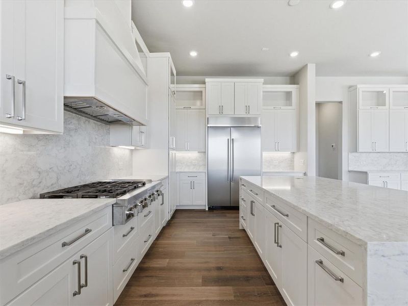 Kitchen featuring light stone counters, glass insert cabinets, white cabinets, tasteful backsplash, and stainless steel appliances