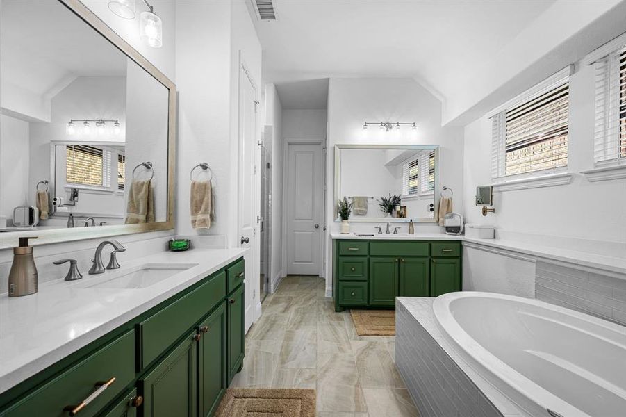 The ensuite primary bathroom features separate vanities, plenty of natural light, and lofted ceiling The ensuite primary bathroom features separate vanities, plenty of natural light, and lofted ceiling
