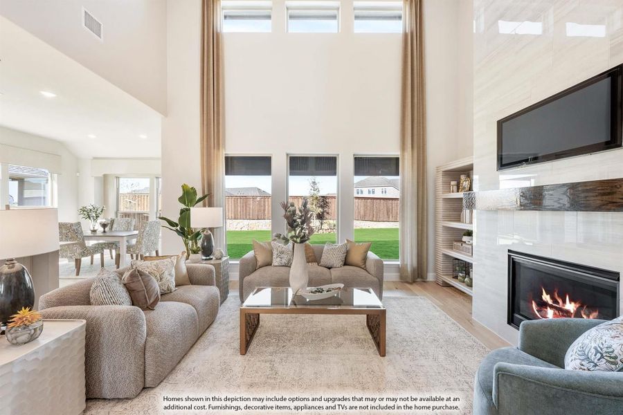 Living room with two-story ceiling, fireplace, built-in shelves, and large windows overlooking backyard