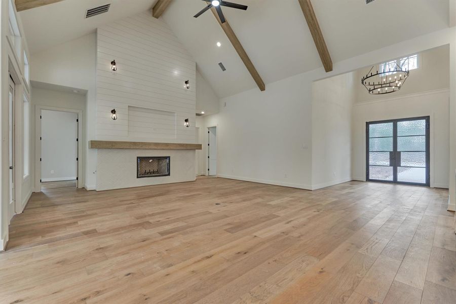 Stylish living room with a dramatic vaulted ceiling, wood beam accents, and a sleek shiplap fireplace anchoring the airy, light-filled space.