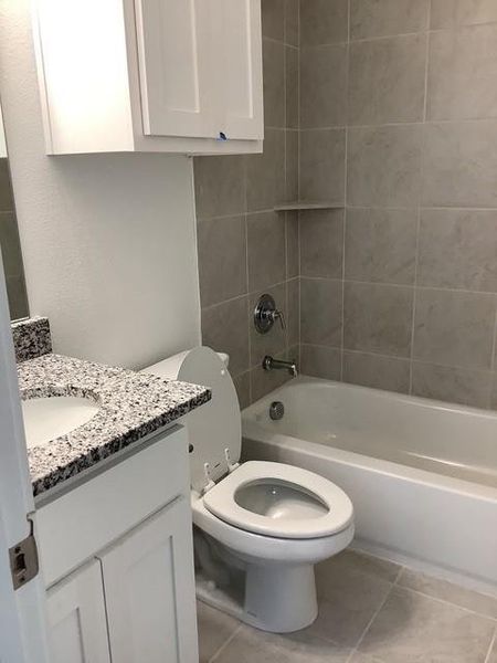 Full bathroom with tiled shower / bath, tile patterned flooring, vanity, and toilet