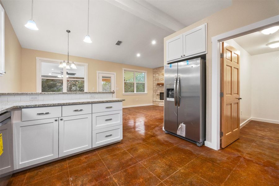 Kitchen featuring white cabinets, stainless steel appliances, hanging light fixtures, light granite countertops, and a chandelier