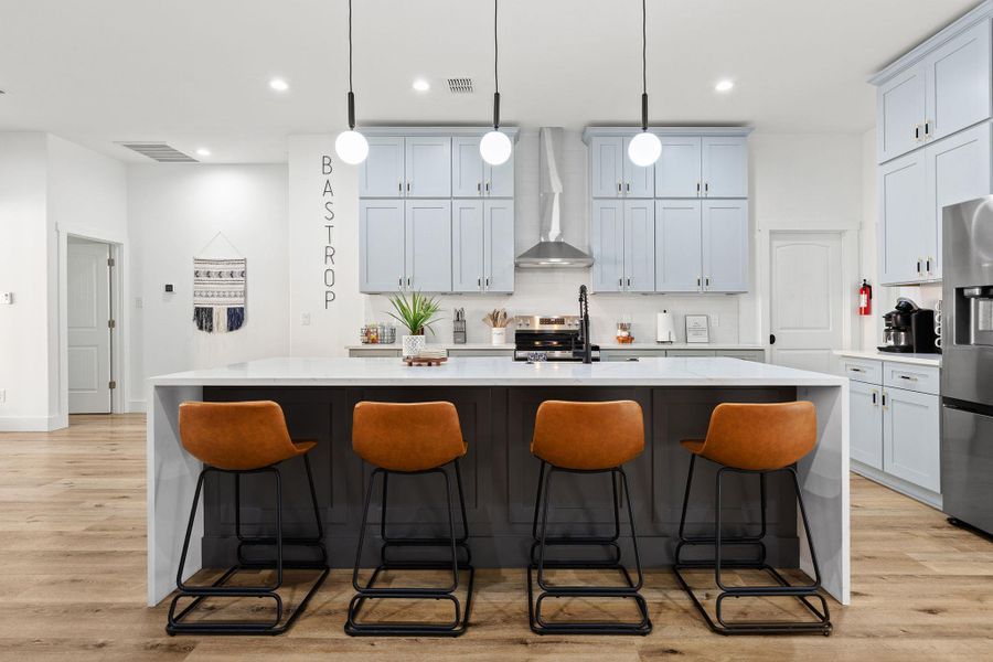 Kitchen with a breakfast bar, an island with sink, light stone counters, backsplash, and recessed lighting