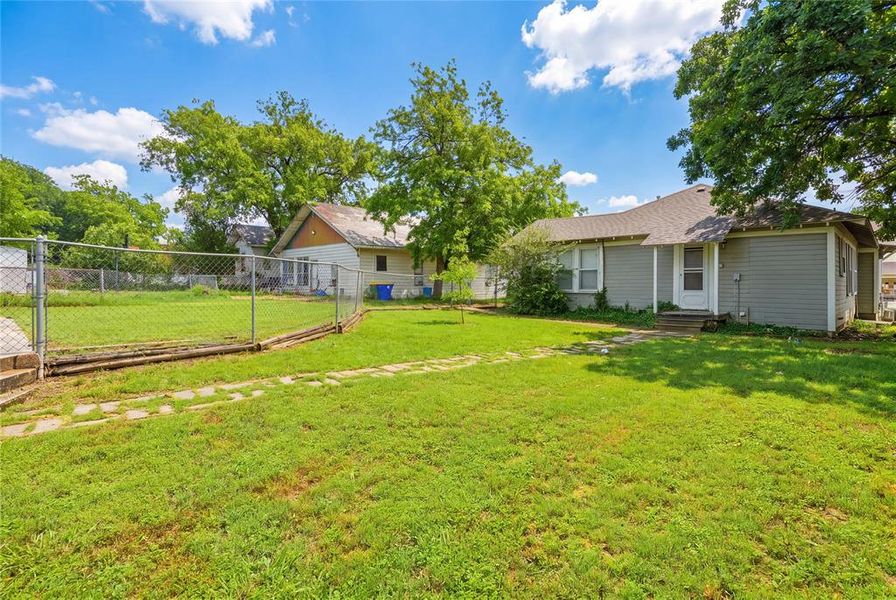 Expansive grassy yard area with a chain-link fence defining a section of the property