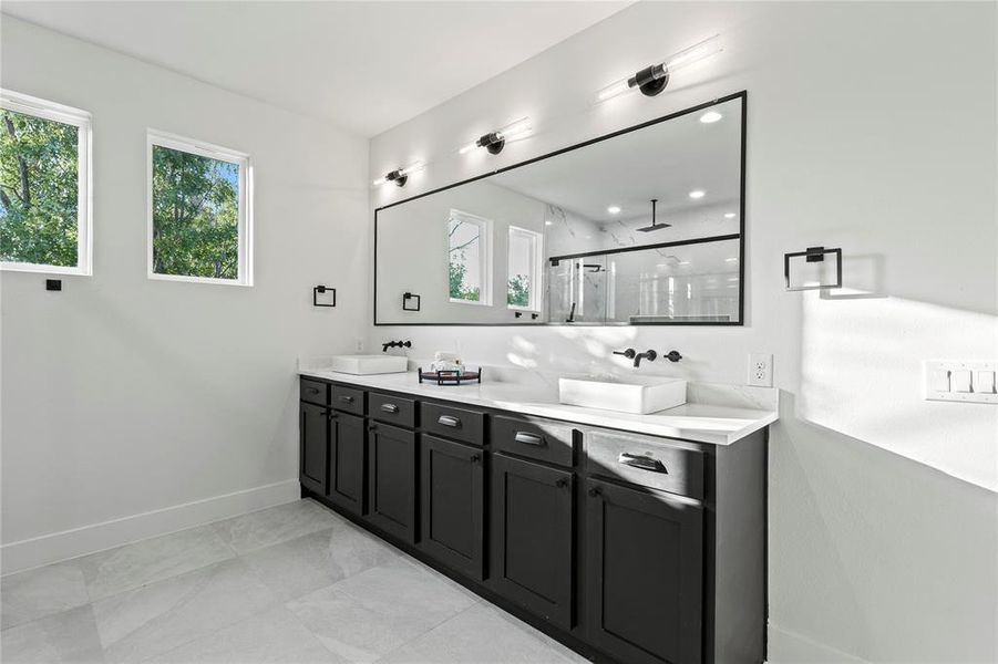 Full bath with double vanity, a shower, and marble look tile flooring