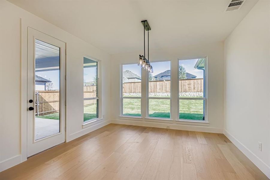 Unfurnished dining area featuring light wood-style floors and baseboards Unfurnished dining area featuring light wood-style floors and baseboards