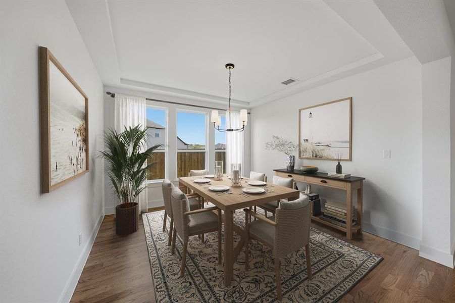 Dining area with a tray ceiling, dark wood-style floors, and a chandelier Dining area with a tray ceiling, dark wood-style floors, and a chandelier