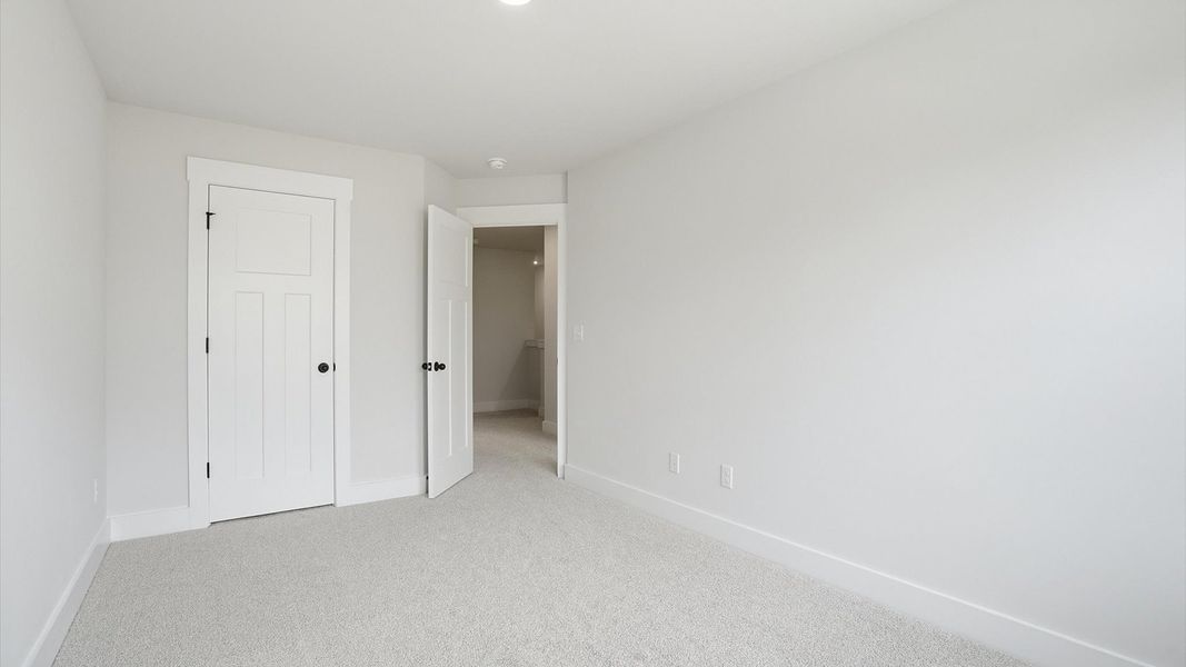 Tasteful secondary bedroom with plush carpet and a spacious walk-in closet at the new Anna's Pointe community