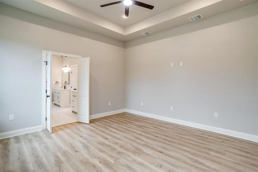 Empty room with visible vents, a ceiling fan, light wood-style floors, and baseboards Empty room with visible vents, a ceiling fan, light wood-style floors, and baseboards