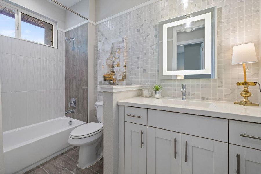 The second bath is adjacent to the bedroom and features a lighted mirror, quartz counter, and tiled shower. The second bath is adjacent to the bedroom and features a lighted mirror, quartz counter, and tiled shower.