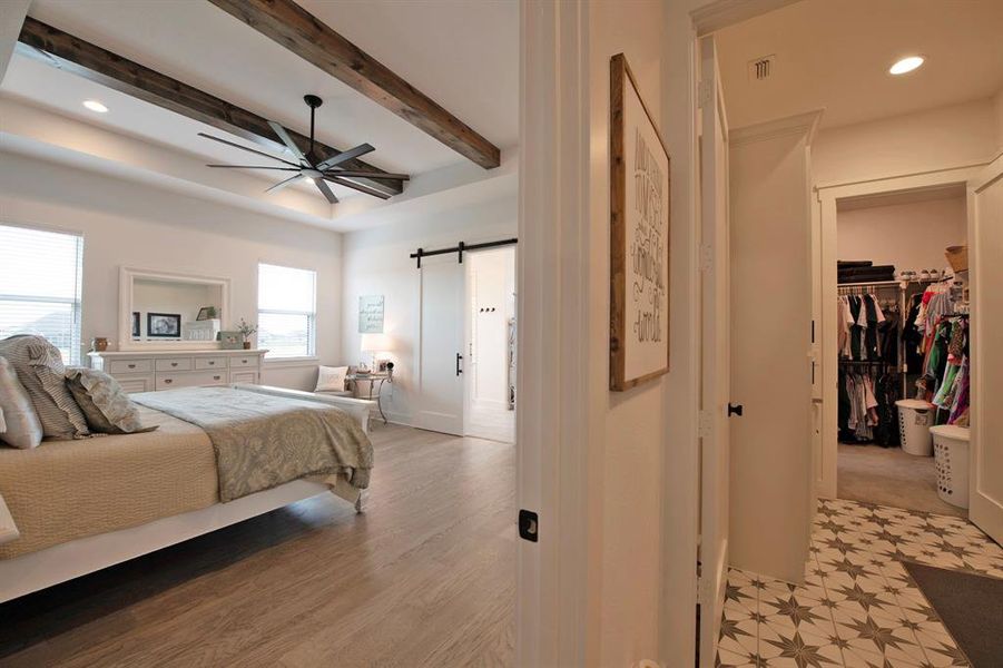 Bedroom featuring a barn door, recessed lighting, a walk in closet, beamed ceiling, and a ceiling fan