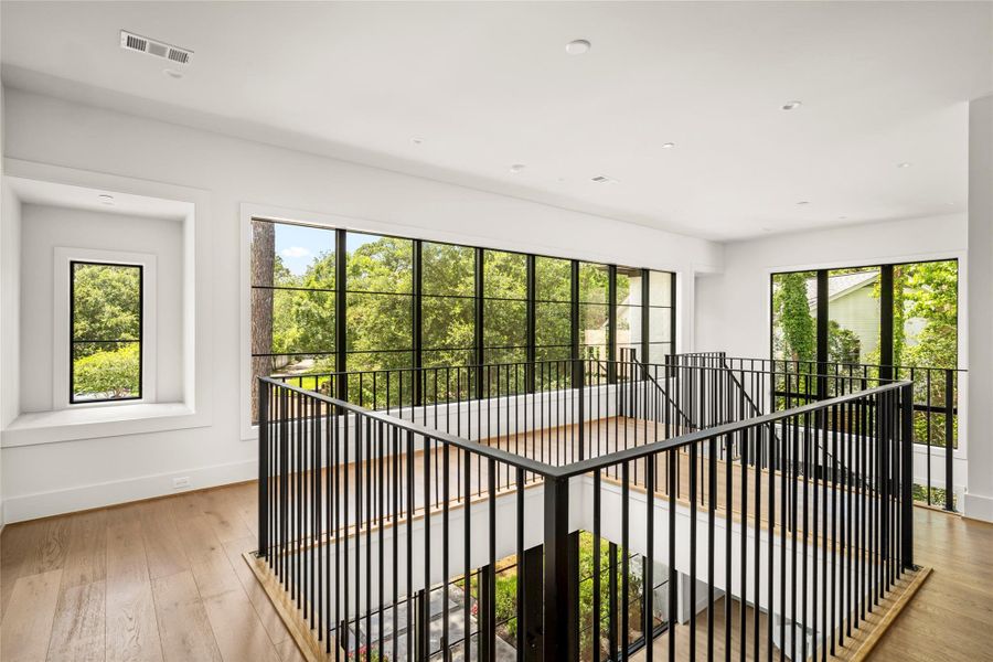 Upstairs sitting area with expanive windows and abundant natural light. Lined with sleek iron railing.
