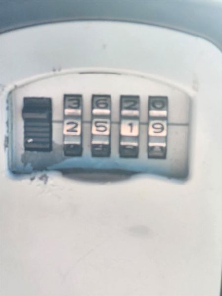 This photo shows a combination lock box, often used for securely storing spare keys outside a home.