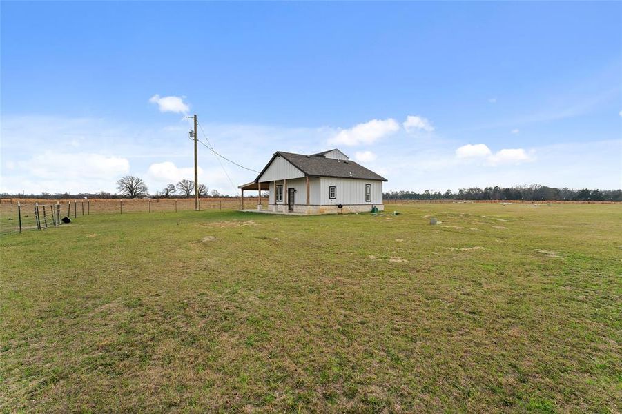 View of green lawn with a rural view and a patio area