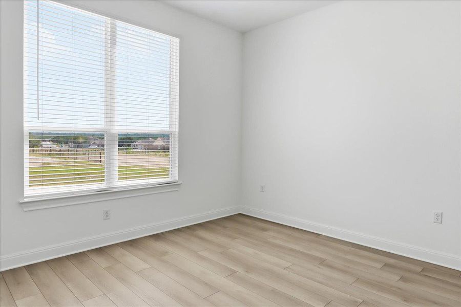 A well-lit room offers durable plank flooring and a window with horizontal blinds overlooking a pleasant neighborhood. A well-lit room offers durable plank flooring and a window with horizontal blinds overlooking a pleasant neighborhood.
