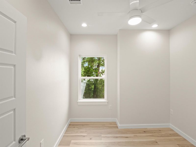 Bright room featuring wood-finish flooring, a white ceiling fan with integrated lighting, recessed lighting, and a window providing natural light