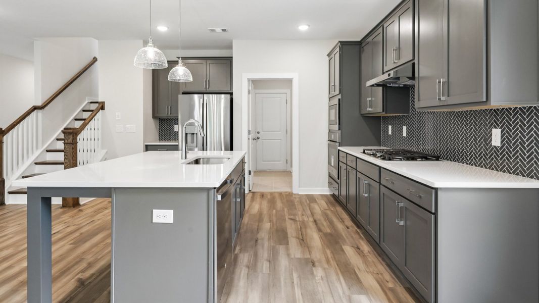 Kitchen with hard surface flooring, quartz countertops, and pendant lighting Kitchen with hard surface flooring, quartz countertops, and pendant lighting