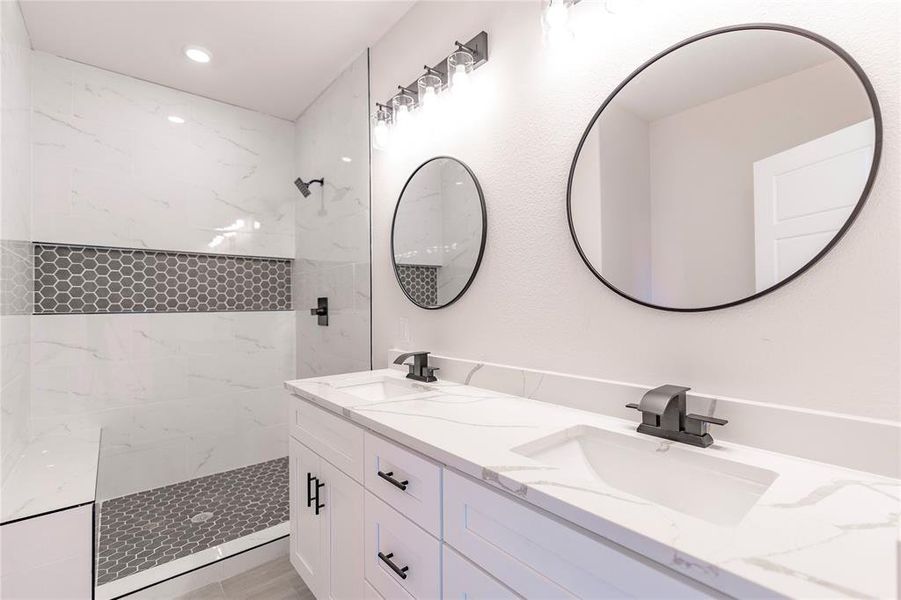 Bathroom with tiled shower and dual vanity