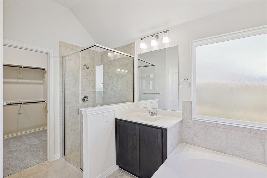 Bathroom featuring tile patterned flooring, vanity, independent shower and bath, and vaulted ceiling