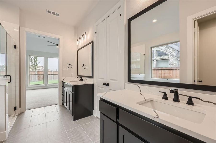 Bathroom with tile patterned flooring, a sink, a shower stall, and visible vents Bathroom with tile patterned flooring, a sink, a shower stall, and visible vents