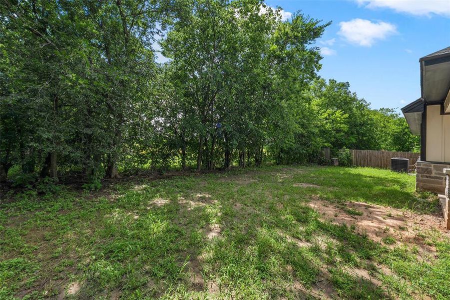 Expansive rear yard featuring mature trees along the perimeter and a partial privacy fence Expansive rear yard featuring mature trees along the perimeter and a partial privacy fence