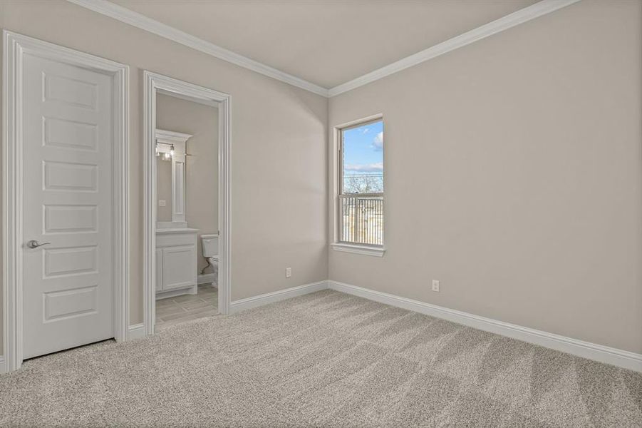 Unfurnished bedroom featuring ensuite bathroom, ornamental molding, and light carpet