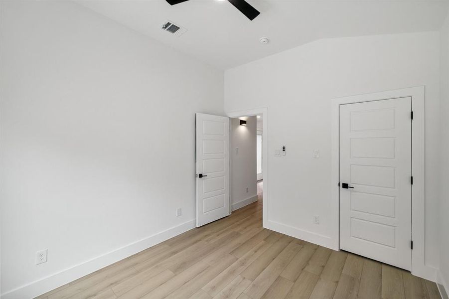 Unfurnished bedroom featuring lofted ceiling, light wood-style flooring, and ceiling fan