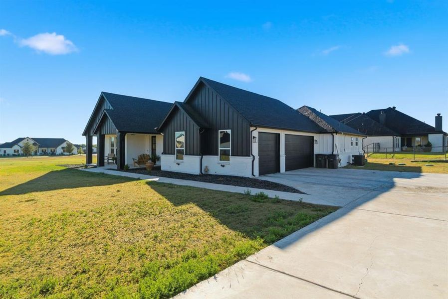 Modern farmhouse with board and batten siding, a front lawn, driveway, and an attached garage