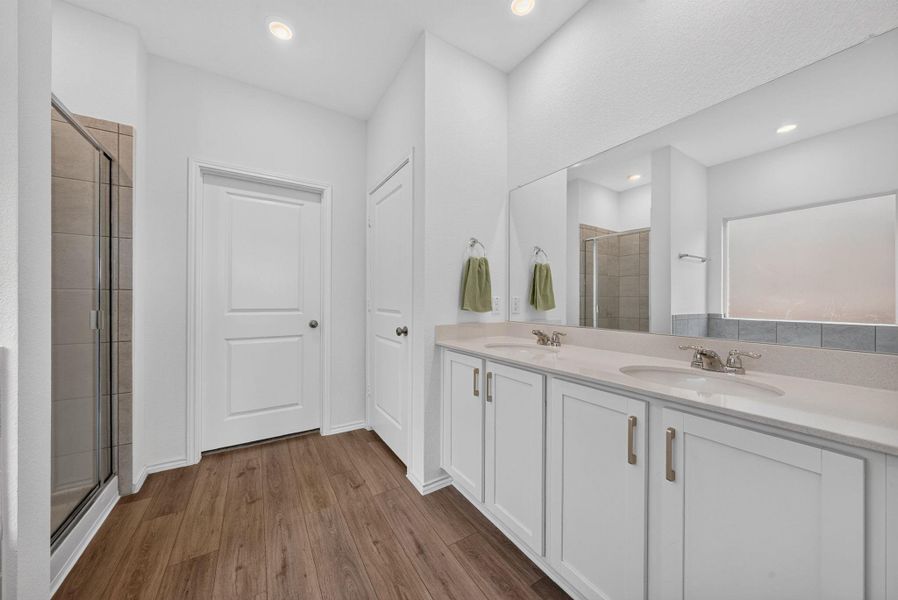 A well-lit primary bathroom featuring dual vanities, modern cabinetry, and a spacious glass-enclosed shower. A well-lit primary bathroom featuring dual vanities, modern cabinetry, and a spacious glass-enclosed shower.