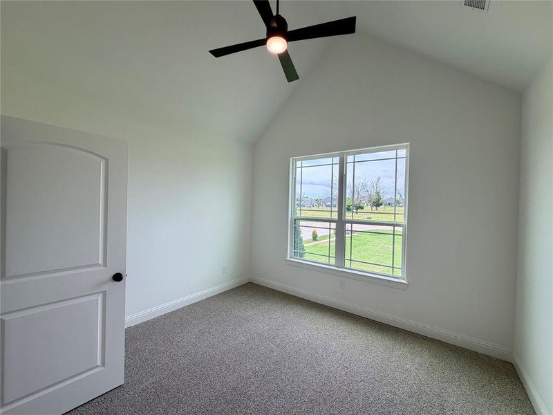 Vaulted ceiling room featuring a large window, neutral carpeting, white trim, and a contemporary ceiling fan