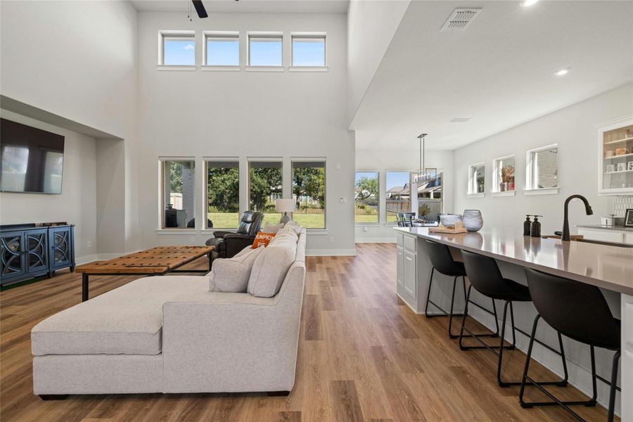 Living area featuring light wood-style floors, a towering ceiling, recessed lighting, and a ceiling fan Living area featuring light wood-style floors, a towering ceiling, recessed lighting, and a ceiling fan