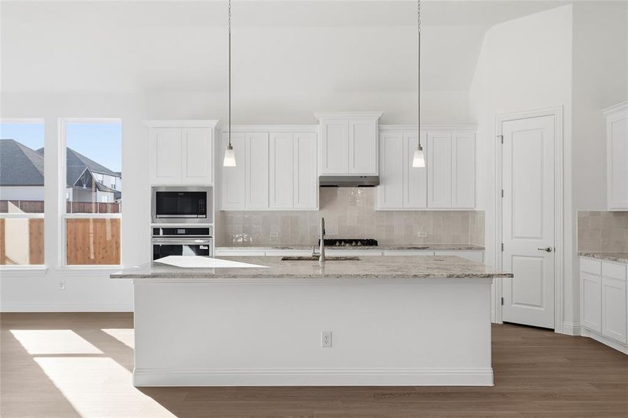 Kitchen with light stone countertops, dark wood-type flooring, backsplash, white cabinets, and appliances with stainless steel finishes Kitchen with light stone countertops, dark wood-type flooring, backsplash, white cabinets, and appliances with stainless steel finishes