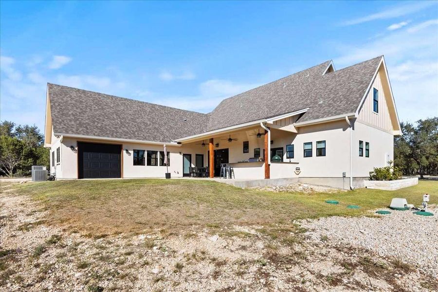 View of front of home featuring a front lawn, a garage, ceiling fan, a patio area, and roof with shingles View of front of home featuring a front lawn, a garage, ceiling fan, a patio area, and roof with shingles