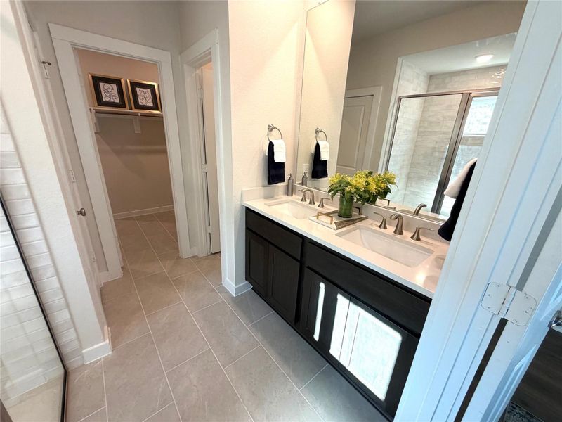 The spacious primary bathroom features dual sinks, a large mirror, bright lights for a luxurious retreat.