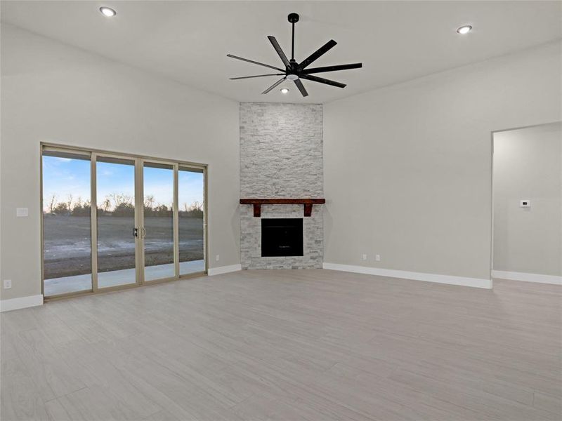 Unfurnished living room featuring a water view, ceiling fan, a fireplace, and light wood-type flooring