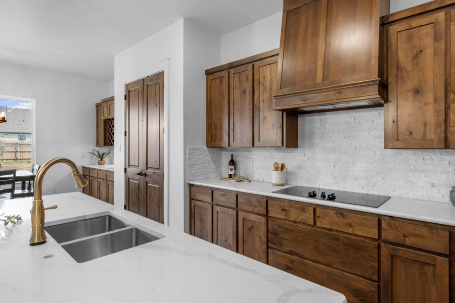 Kitchen featuring light stone countertops, black electric cooktop, and backsplash