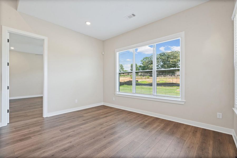 Room featuring wood-finish flooring, recessed lighting, and light-toned walls Room featuring wood-finish flooring, recessed lighting, and light-toned walls