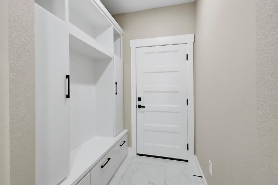 Step directly from the garage into a beautifully organized transition space. This custom-built mudroom features sleek white cabinetry, upper cubbies, deep storage drawers, and a built-in bench seat. Step directly from the garage into a beautifully organized transition space. This custom-built mudroom features sleek white cabinetry, upper cubbies, deep storage drawers, and a built-in bench seat.