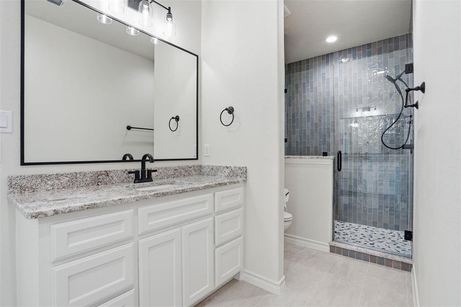 Bathroom featuring a shower stall, vanity, and light tile patterned floors Bathroom featuring a shower stall, vanity, and light tile patterned floors