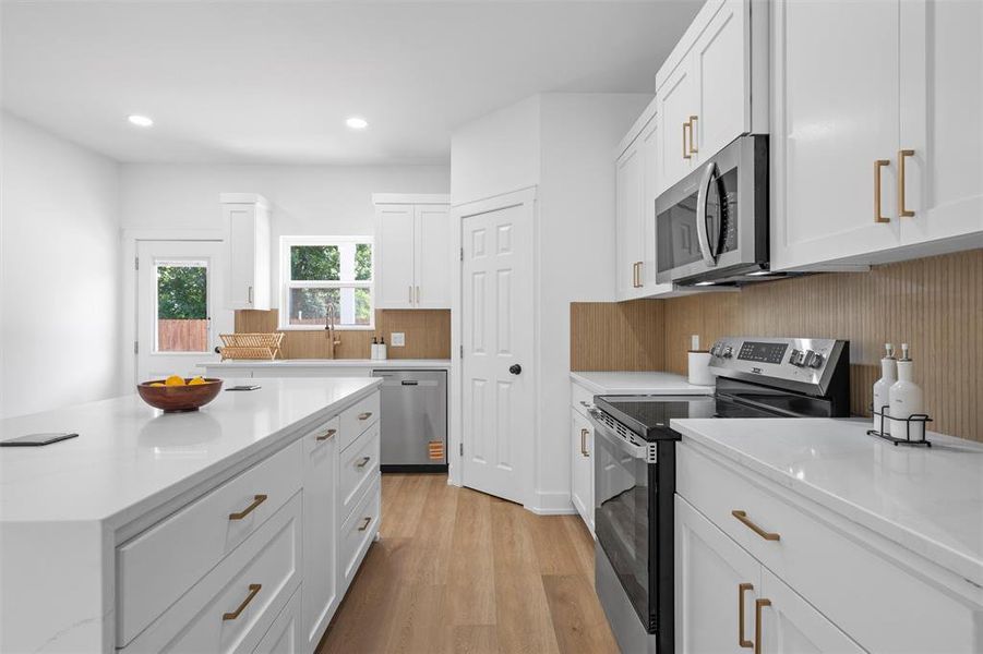 Kitchen featuring appliances with stainless steel finishes, light wood finished floors, white cabinets, recessed lighting, and tasteful backsplash Kitchen featuring appliances with stainless steel finishes, light wood finished floors, white cabinets, recessed lighting, and tasteful backsplash