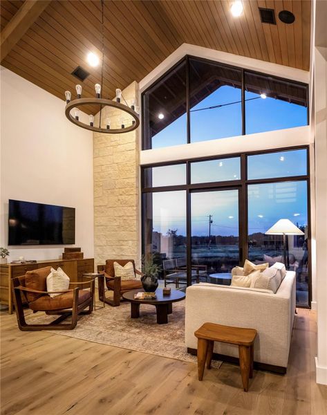 Evening living room ambiance with soaring glass walls, vaulted ceilings, and warm designer lighting throughout the space.