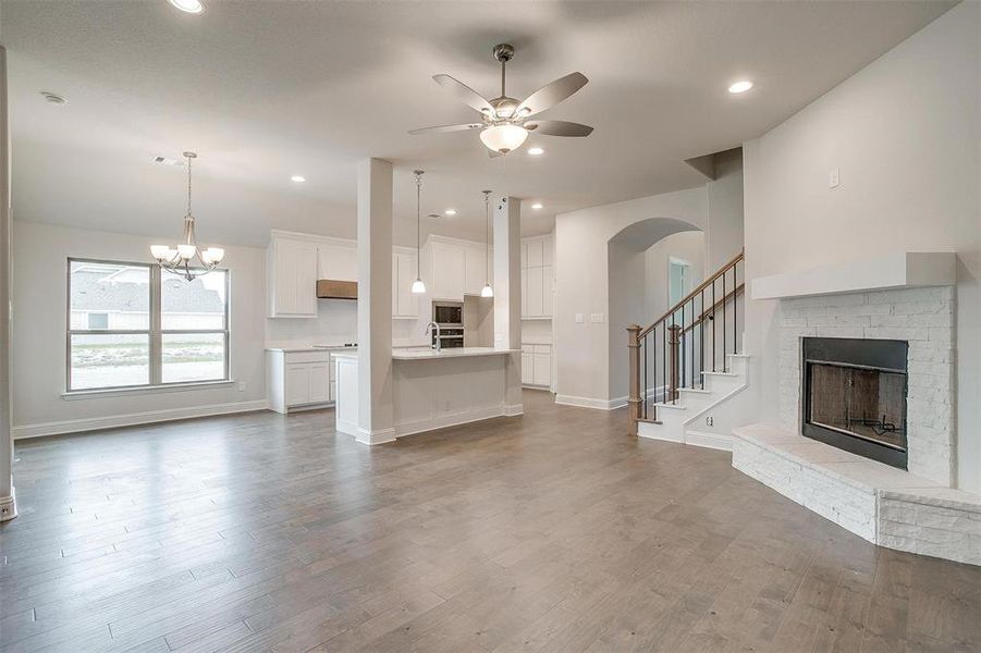 Unfurnished living room featuring ceiling fan with notable chandelier, dark hardwood / wood-style flooring, a fireplace, and sink